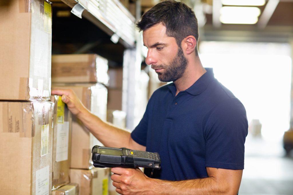 Warehouse worker using barcode scanner in distribution warehouse