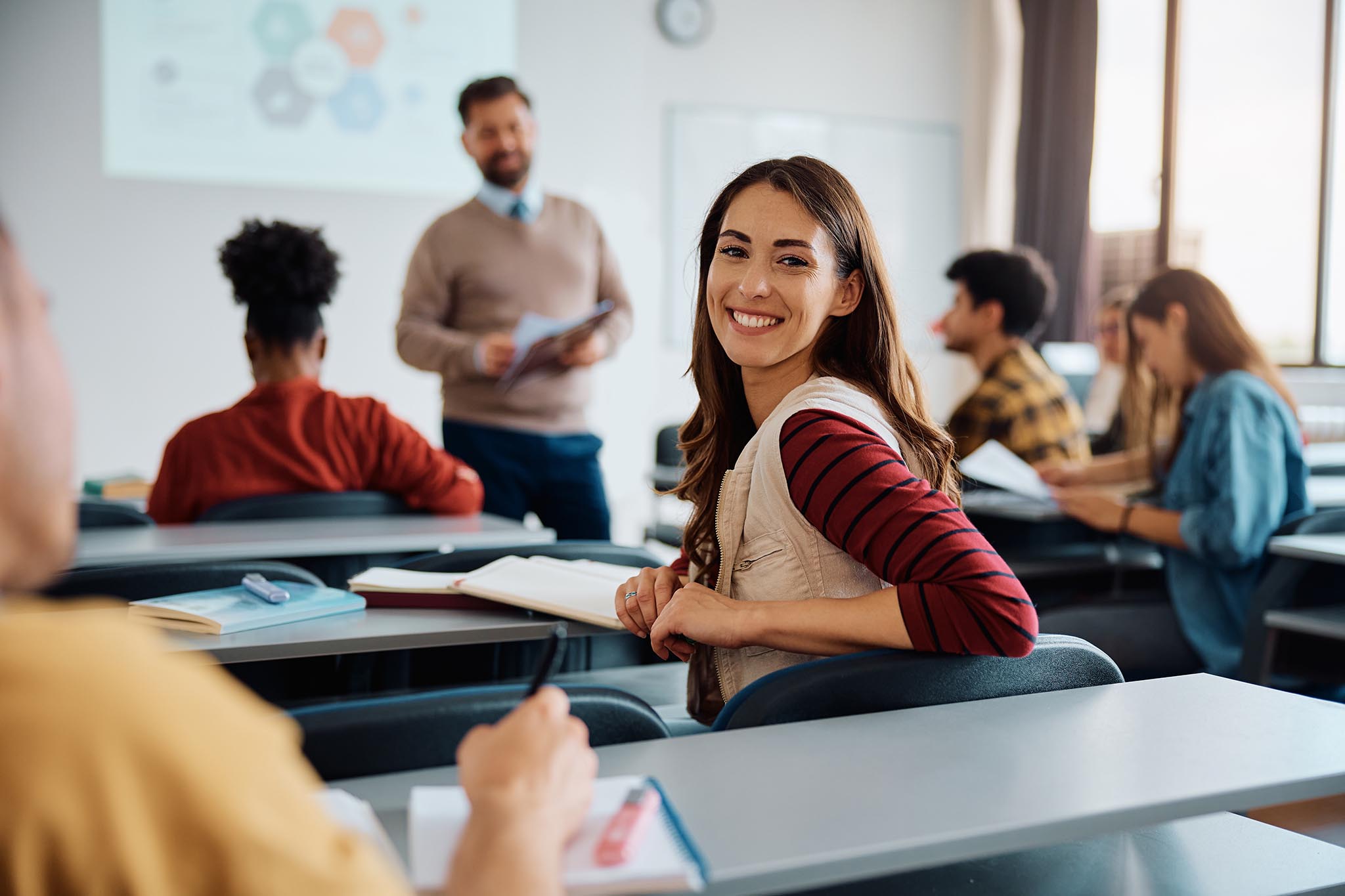 Happy female student attending class at university and looking at camera.