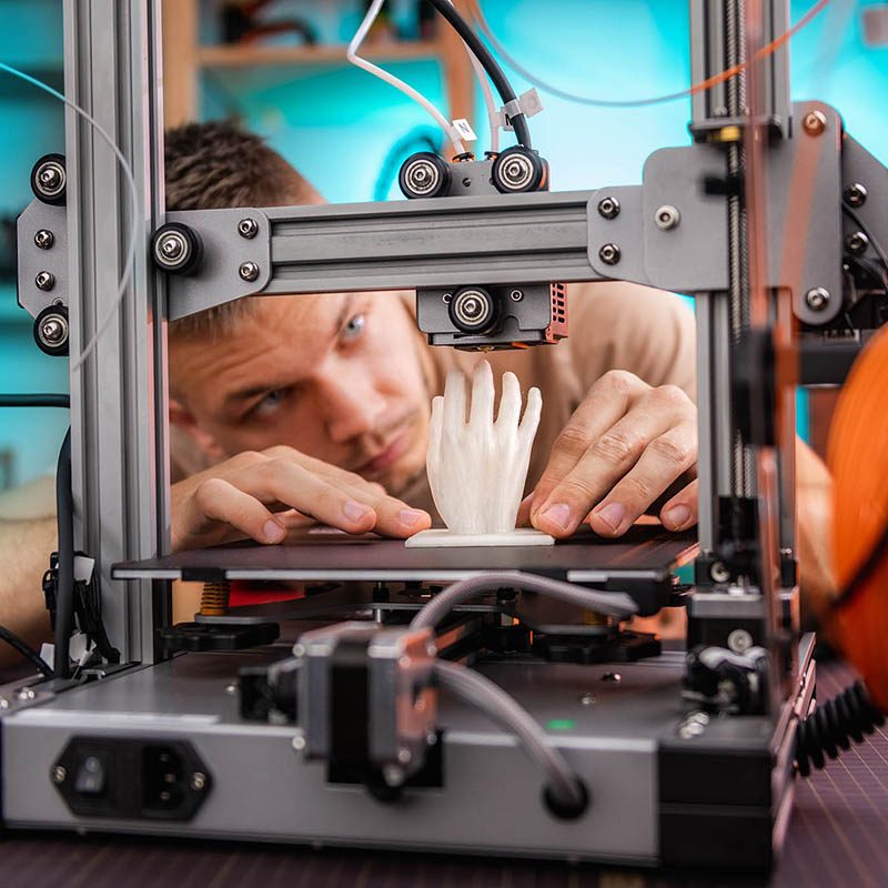 student in the workshop examines the detail printed on a 3D printer.